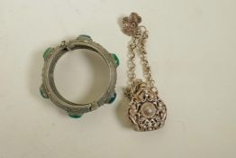 A Chinese white metal bangle set with green jade stones and a white metal scent holder pendant,