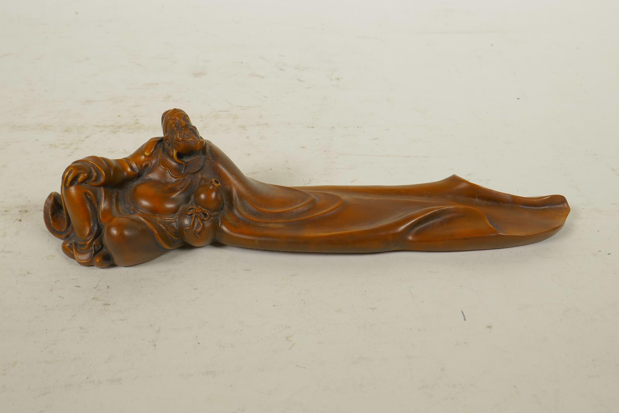 A Chinese boxwood incense stick holder in the form of a reclining sage, 8" long