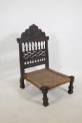 An antique Indian Pidha chair with a carved and pierced hardwood back, a woven seat, and metal