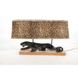 A vintage porcelain table lamp in the form of a jaguar, mounted on a wood plinth, with faux hide