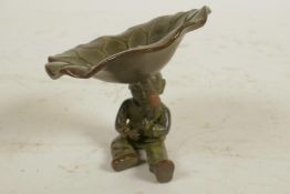 A Chinese bronze figure of a seated boy holding a large lily leaf, 2½" high