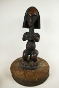 An African carved hardwood figure mounted as the handle to a large lid, 19" high