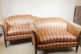 A pair of two seater settees, with scroll arms and hump backs, raised on reeded tapering supports,