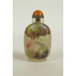 A Chinese reverse decorated glass snuff bottle depicting figures in a mountain landscape and