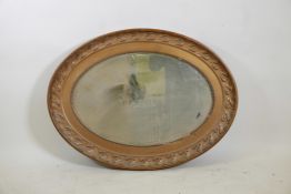 A C19th oval gilt mirror with a leaf design, 39½" x 29½"