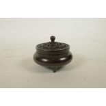 A Chinese bronze censer with a pierced cover and tripod supports, decorated with bats to cover and