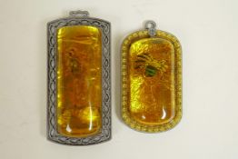 A Chinese faux amber and metal pendant containing a scorpion, and another similar containing a