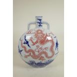 A Chinese blue and white porcelain two handled moon flask decorated with a red dragon in flight