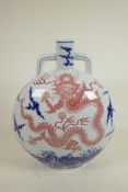 A Chinese blue and white porcelain two handled moon flask decorated with a red dragon in flight