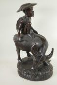 An Oriental carved hardwood figure of a man seated on a buffalo, 23" high