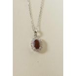 An 18ct white gold pendant necklace set with a garnet encircled by diamonds