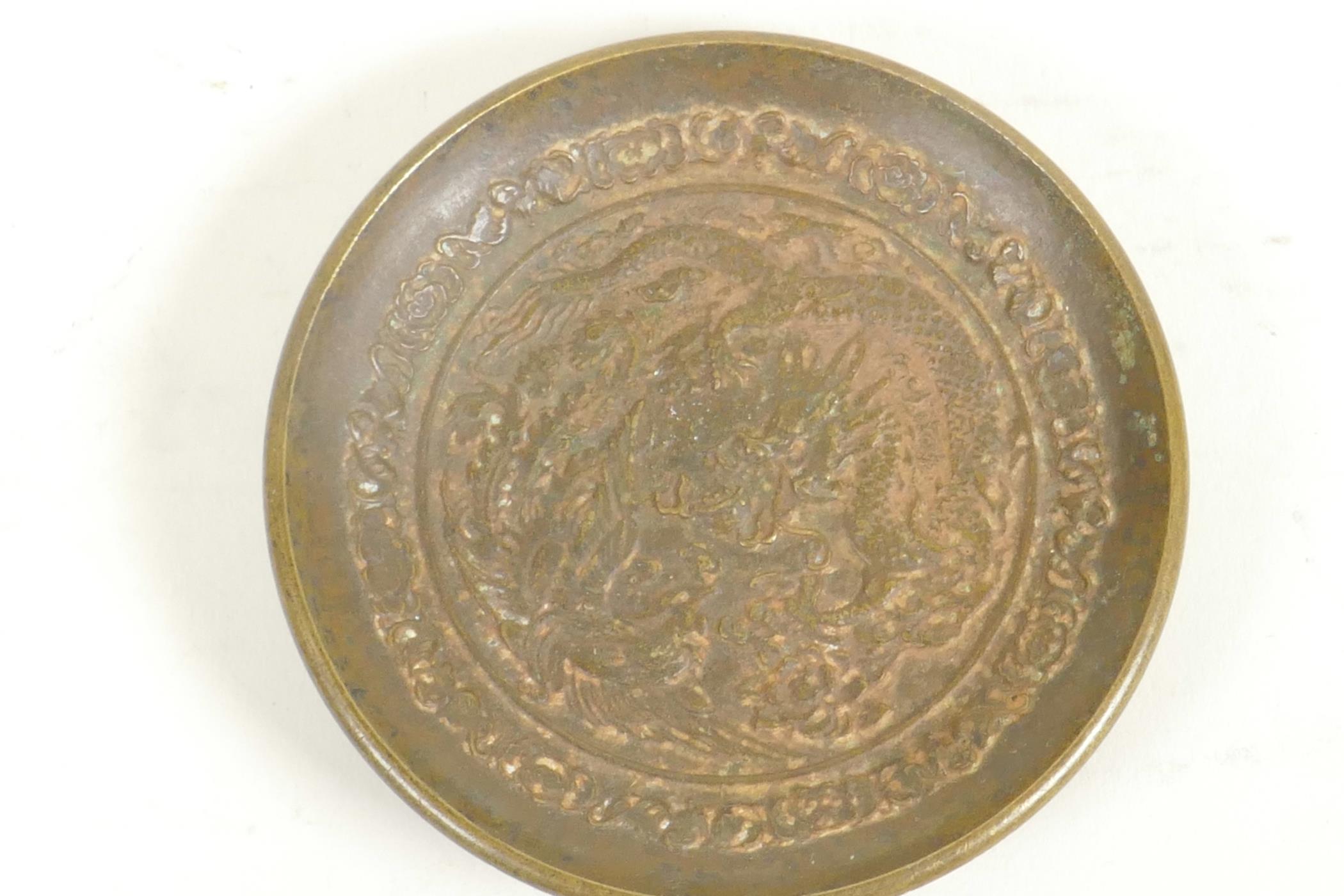 A Chinese bronze pin tray embossed with a fiery dragon, 3" diameter