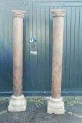 Architectural salvage: A pair of Indian teak columns with carved capitals, mounted on carved stone