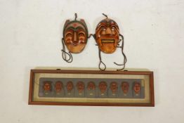 Two Korean carved and painted wood masks and a framed set of similar miniature masks, 28" x 8"