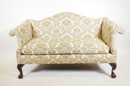 A Chippendale style two seater humpback settee with scroll arms, raised on carved cabriole