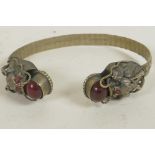 A Chinese white metal bangle, the terminals made as dragons' heads set with semi-precious stones,