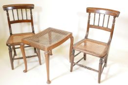 A pair of mahogany, cane seated spindle back side chairs, and a walnut footstool with a cane seat,