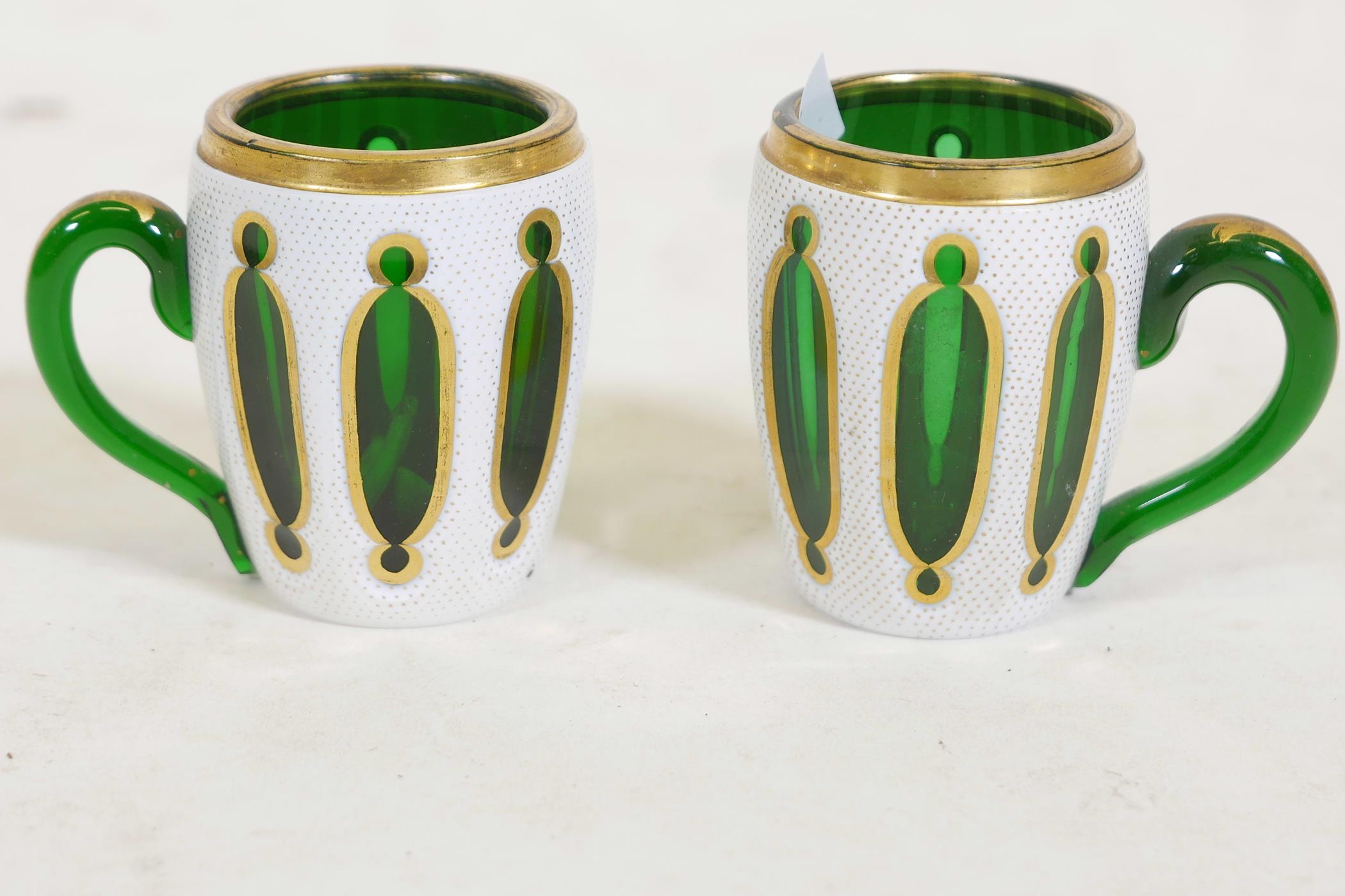 A pair of Bohemian overlaid and gilt glass mugs, 3½" high