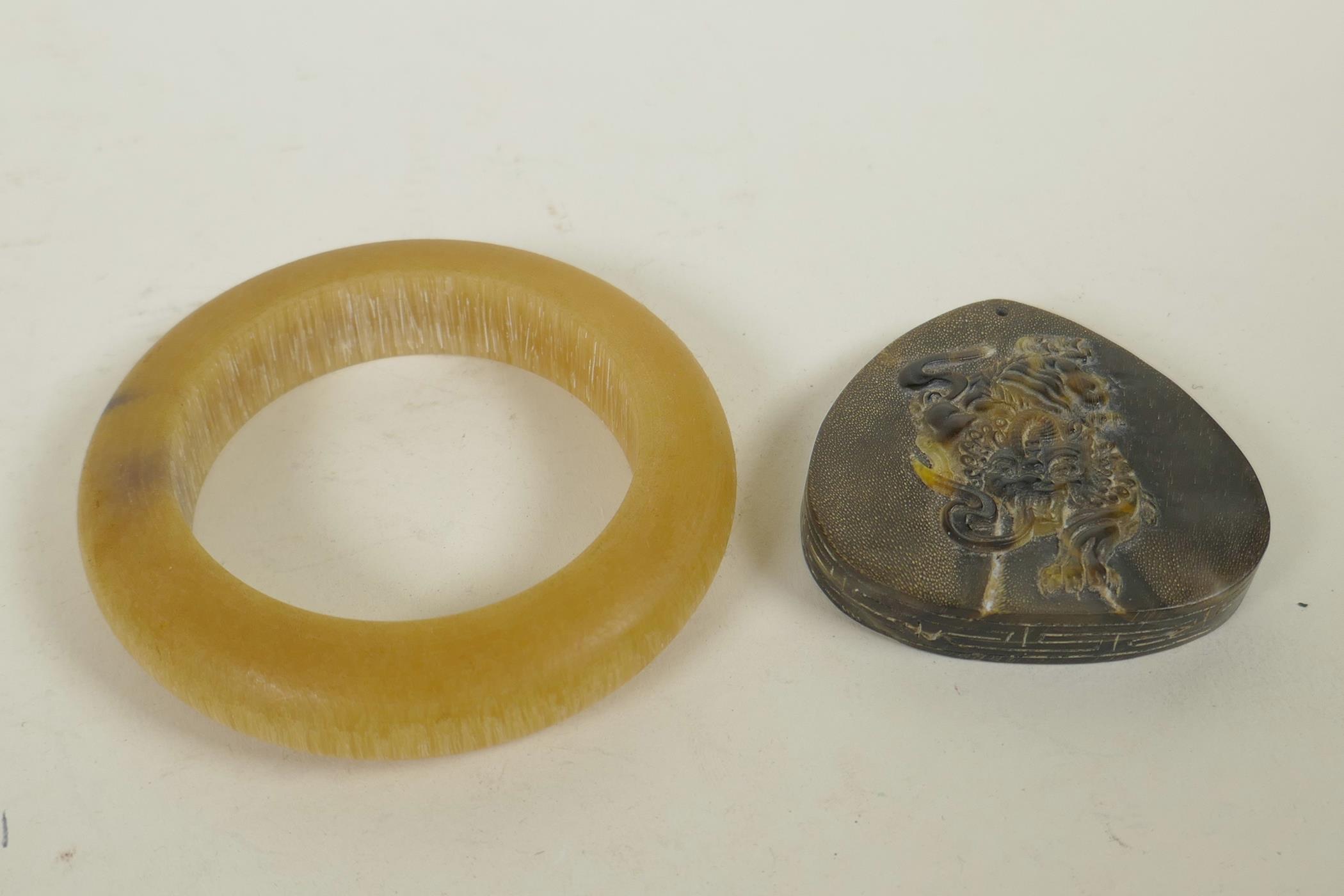 A Chinese faux horn bangle, and a horn pendant with carved kylin decoration, 3½" diameter