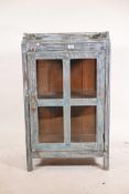 An Indian hardwood single door display cabinet with three quarter gallery top and glazed sides,