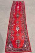 A Iranian full pile runner with a floral pattern on a rich red ground, 39" x 170"