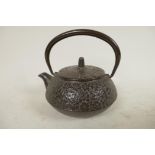 A small Japanese iron teapot with all over floral decoration, 4¼" diameter