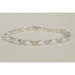 A silver bracelet set with alternating cubic zirconium and opalite, 7" long