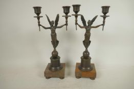 A pair of bronze two branch candelabra, the torch pattern sconces supported by angels, 13" high