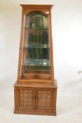 An American light oak display cabinet of tapering form, with mirrored back and single door over