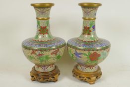 A pair of Chinese cloisonne vases decorated with flowers, on carved wood stands, 9" high