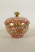 A Chinese red and white porcelain rice bowl and cover with floral decoration highlighted with