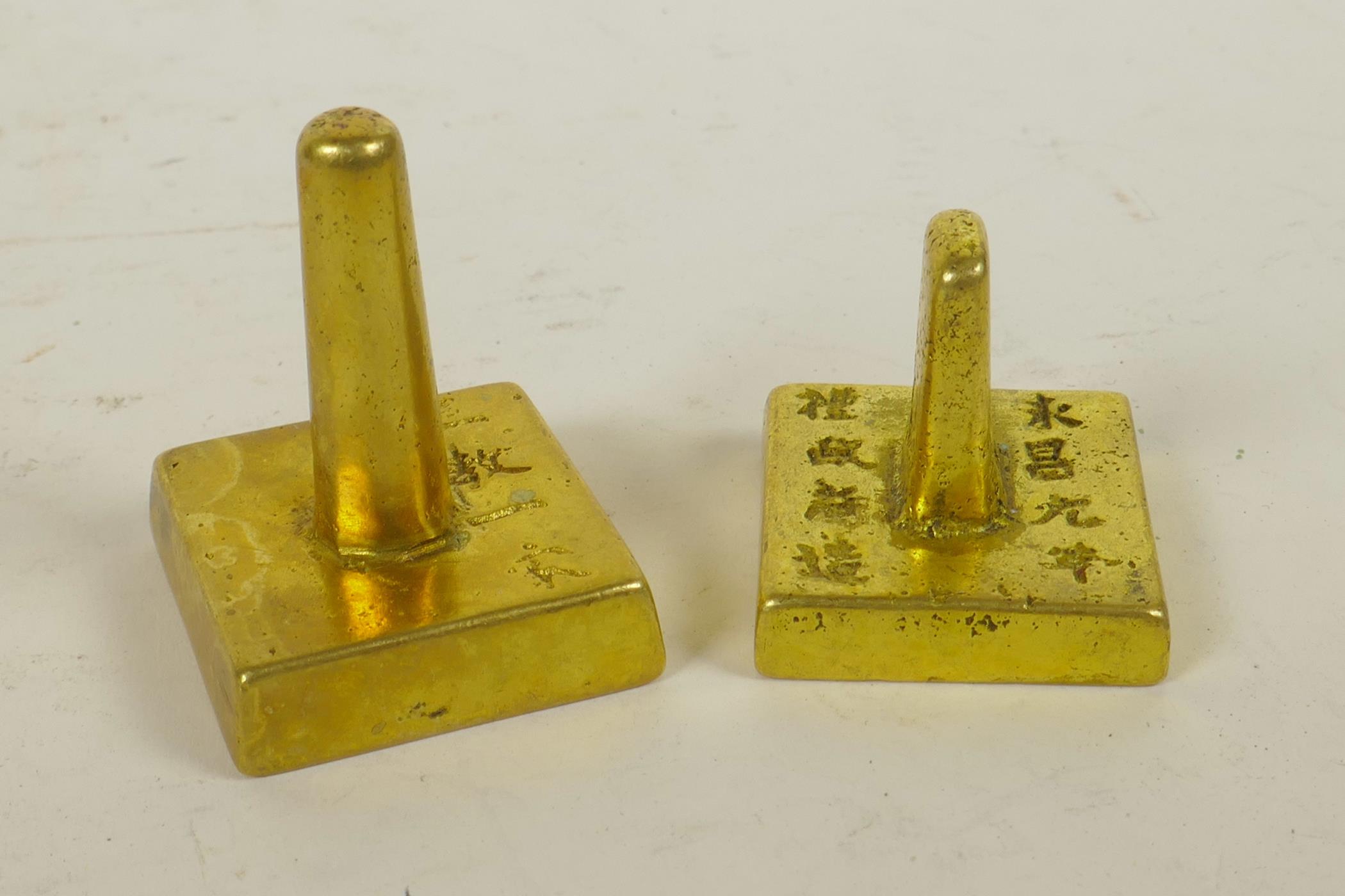 A Chinese gilt metal seal of square form and another similar, the tops with character
