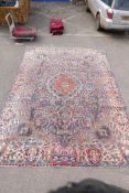 A vintage Persian Kashmar carpet decorated with a floral medallion on a purple ground, and a cream