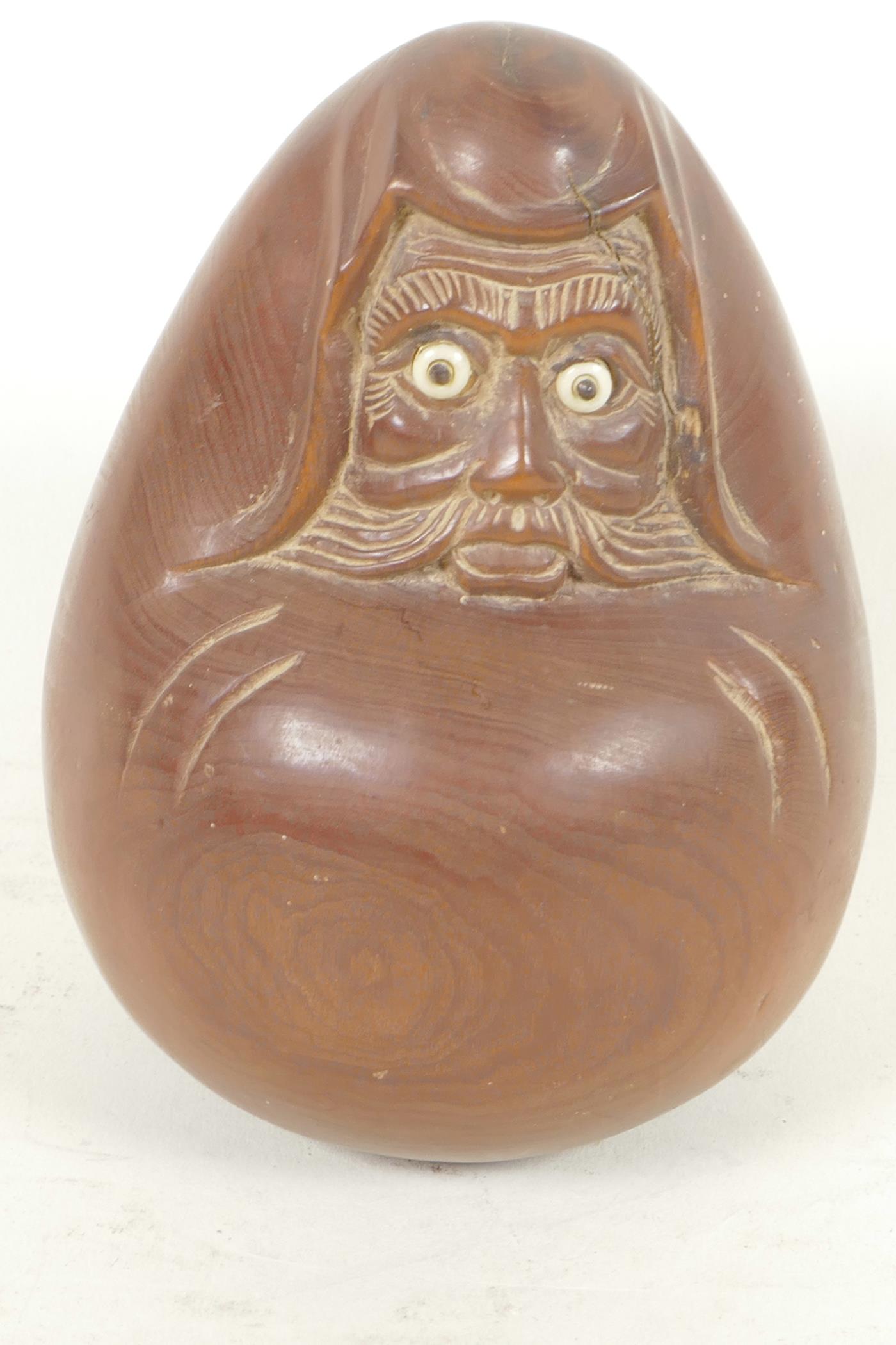 A Japanese carved hardwood okimono figure of a rounded man with bone and glass eyes, character