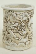 A Chinese white glazed porcelain brush pot with embossed dragon decoration, 5½" high