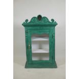 An Indian painted hardwood cabinet with single glazed door and shaped pediment with inset mirrored