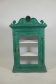 An Indian painted hardwood cabinet with single glazed door and shaped pediment with inset mirrored