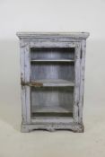 An Indian painted hardwood cabinet with single glazed door, raised on a shaped plinth, 24" x 8" x