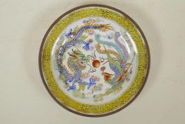A Chinese Canton enamelled copper shallow saucer, decorated with a dragon and phoenix, 5"