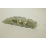 A Chinese celadon jade belt buckle with carved dragon decoration, 5½" long