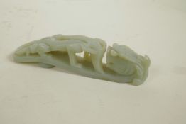 A Chinese celadon jade belt buckle with carved dragon decoration, 5½" long