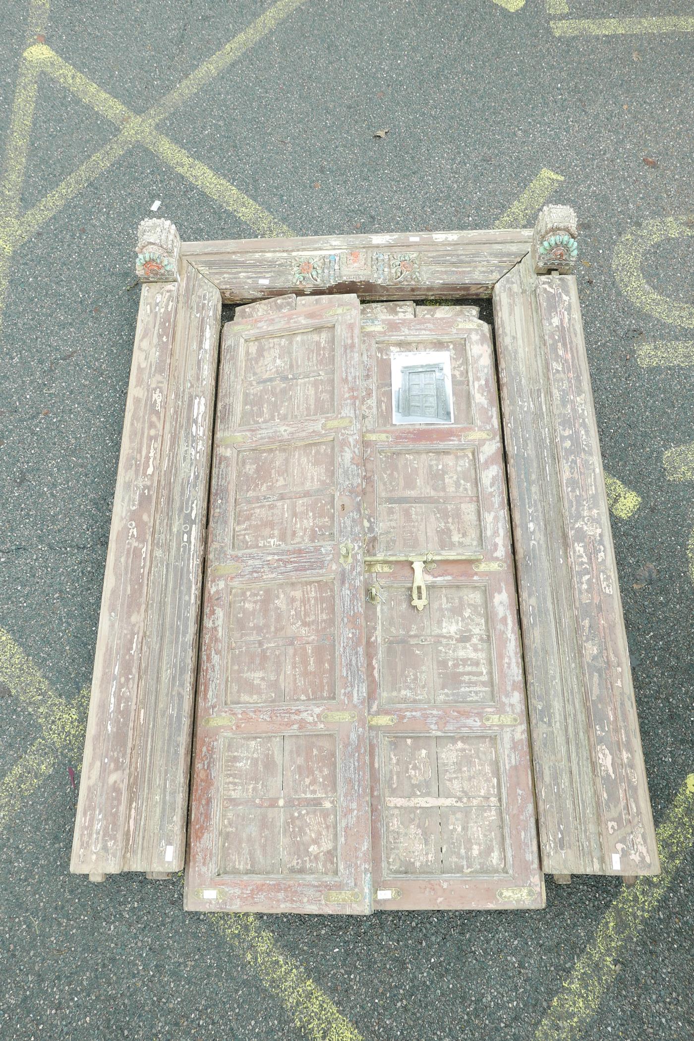 Architectural salvage: A pair of Indian teak storm doors and frame, with carved details, each door