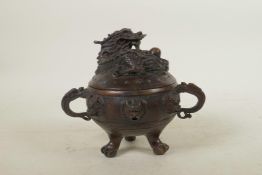 A Chinese bronze censer and cover with two dragon shape handles, tripod pawed feet, dragon mask