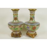 A pair of Chinese cloisonne vases decorated with flowers, on carved wood stands, 9" high