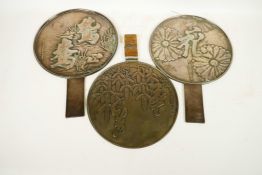 Three earl C19th Japanese bronze hand mirrors, the backs decorated with flowers and calligraphy,