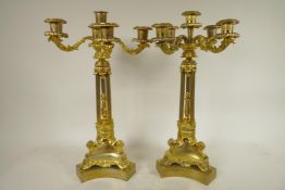 A pair of ornate ormolu four branch candlesticks with triple reeded columns and triform base, all