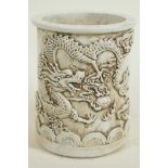 A Chinese white glazed porcelain brush pot with embossed dragon decoration, 5½" high