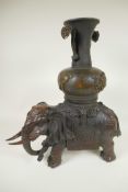 An oriental bronze figure of an ornately dressed elephant with a large vase on his howdah, 16½" high