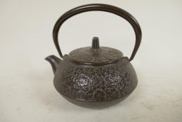 A small Japanese iron teapot with all over floral decoration, 4¼" diameter