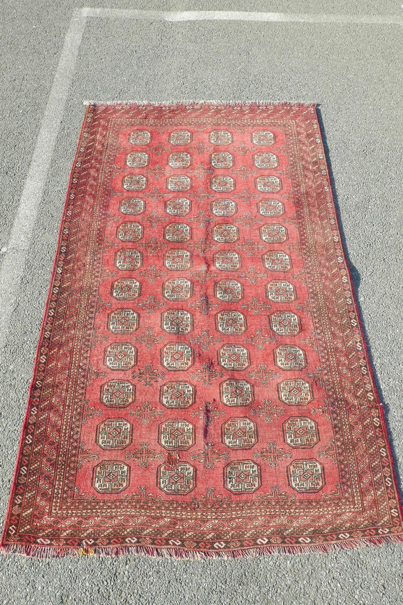 A washed red ground Turkmen carpet with a Bokhara design, repairs, 56" x 90"